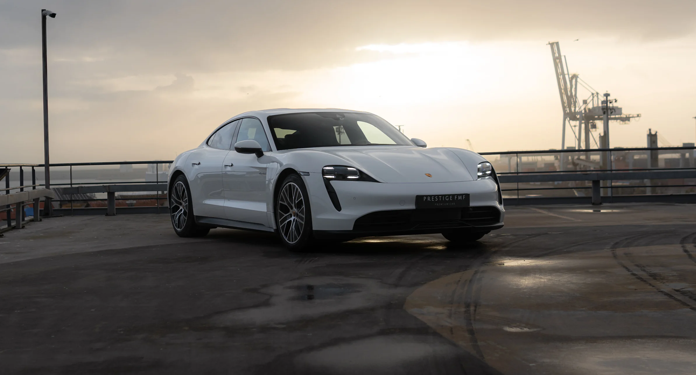 Porsche Taycan branco ao pôr do sol, junto ao porto